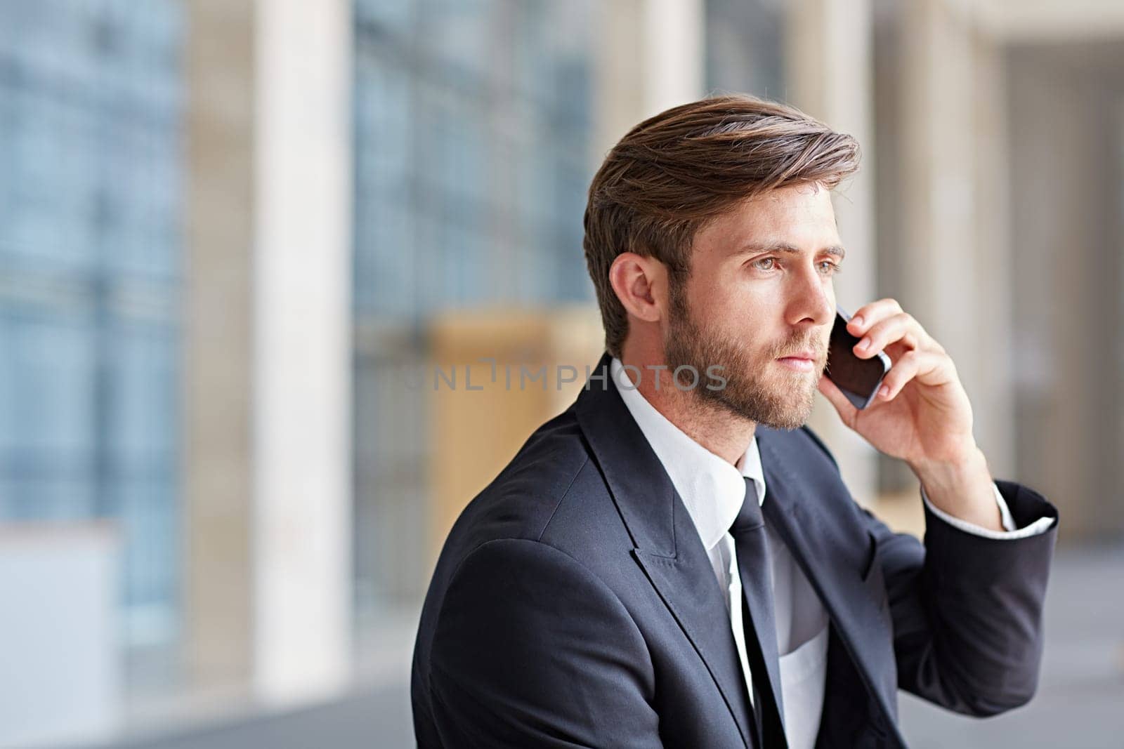 Corporate executive using his cell phone in a modern architectural setting
