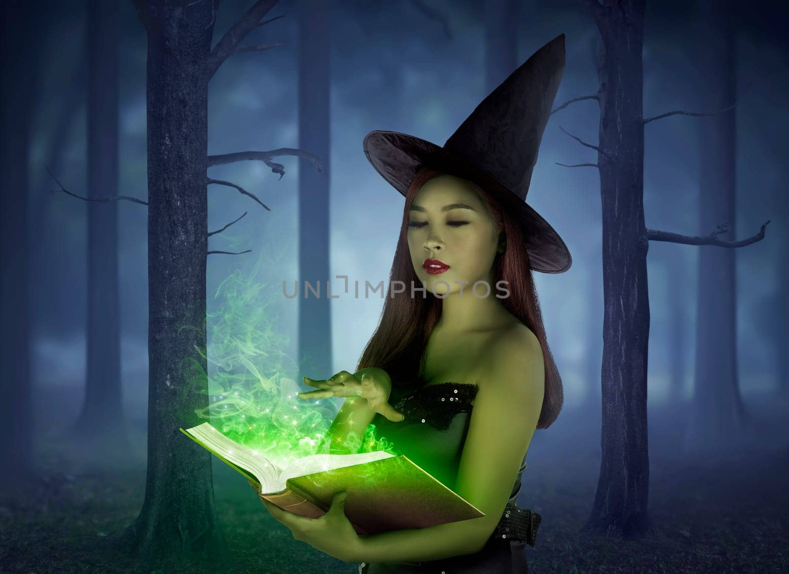 Beautiful asian girl wearing witch cloth reading spell in the book on the forest at night