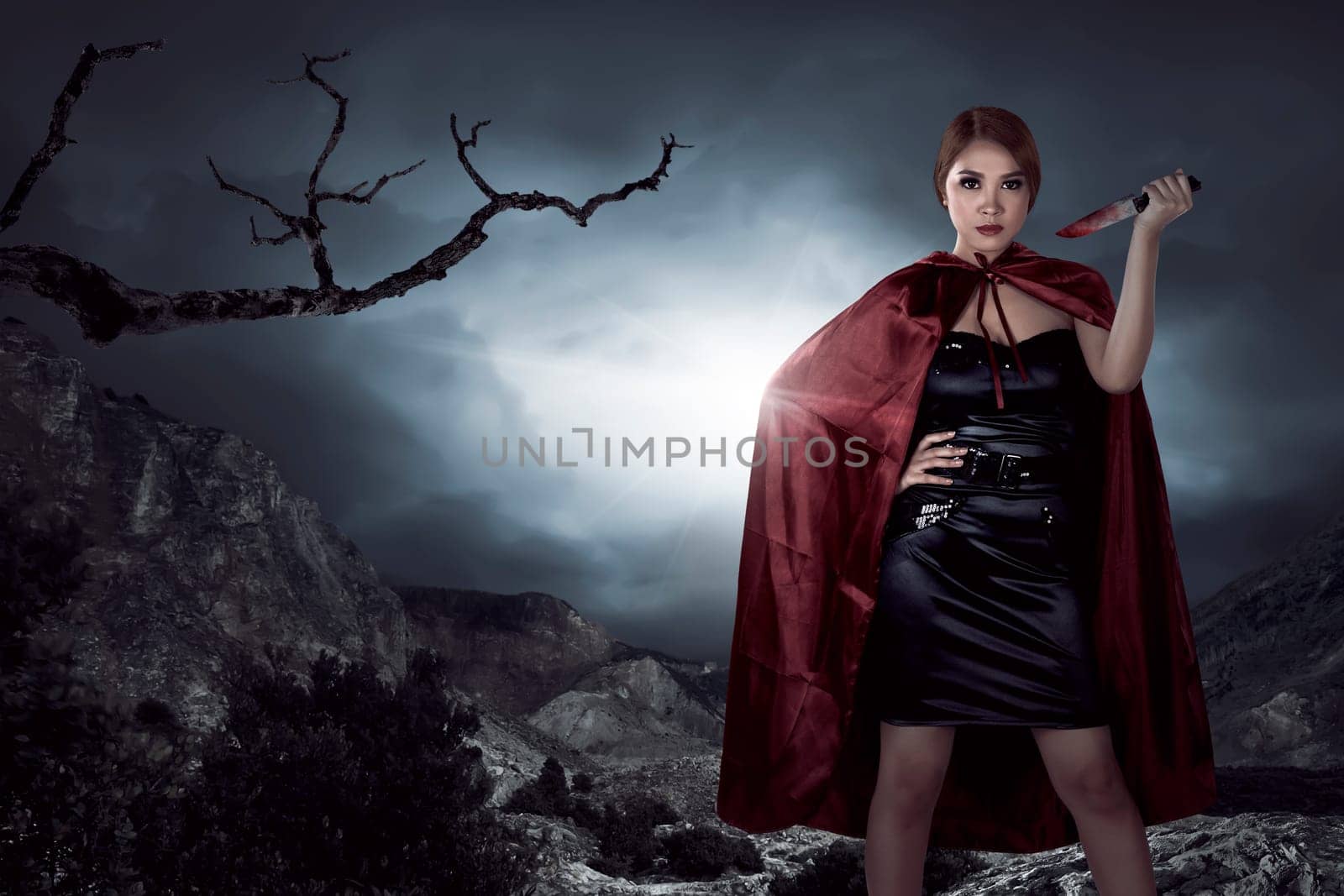 Beautiful asian witch woman holding bloody knife in the night, horror situation. Halloween concept image