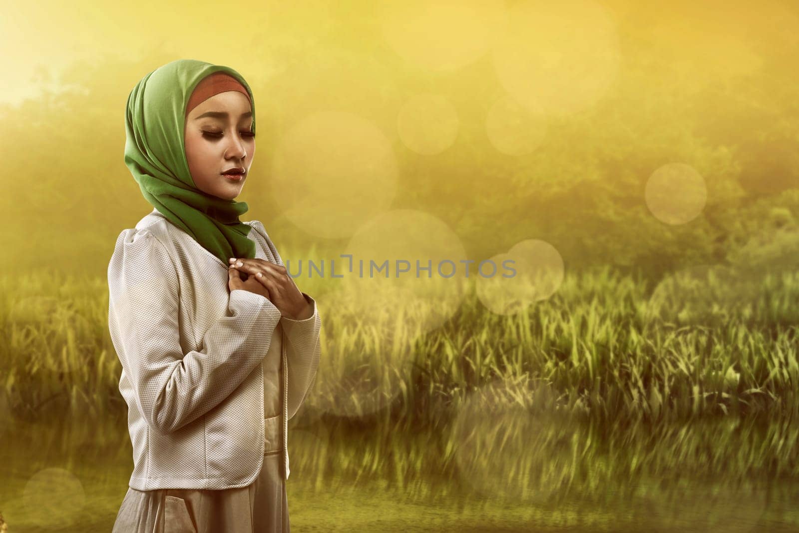 Image of asian muslim woman praying on the field