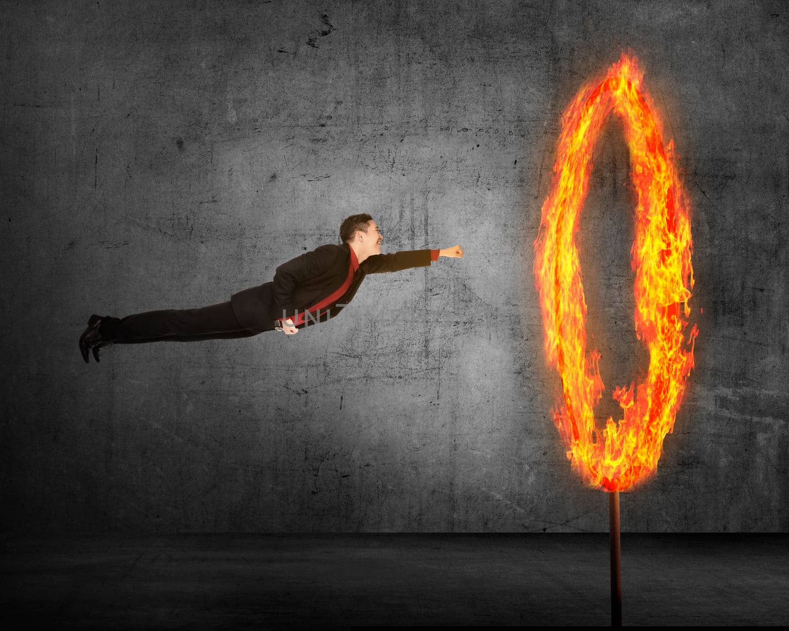 Asian business person flying through ring of fire. Business risk conceptual