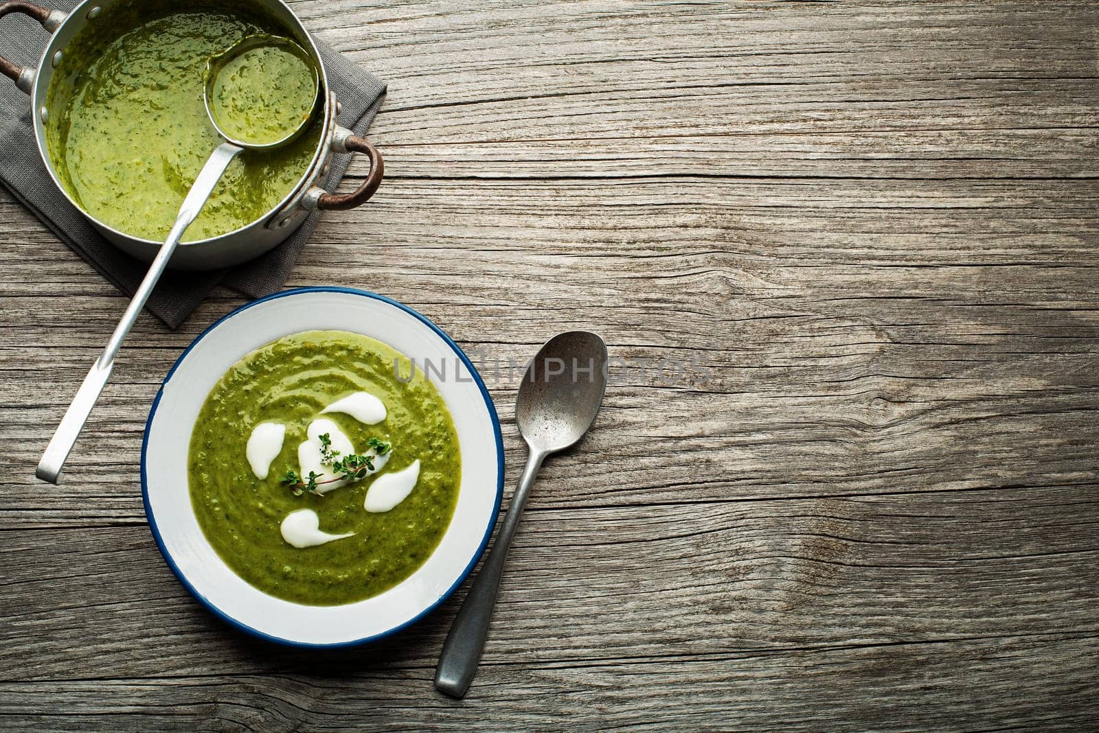 Fresh healthy green soup on wooden background overhead shoot.