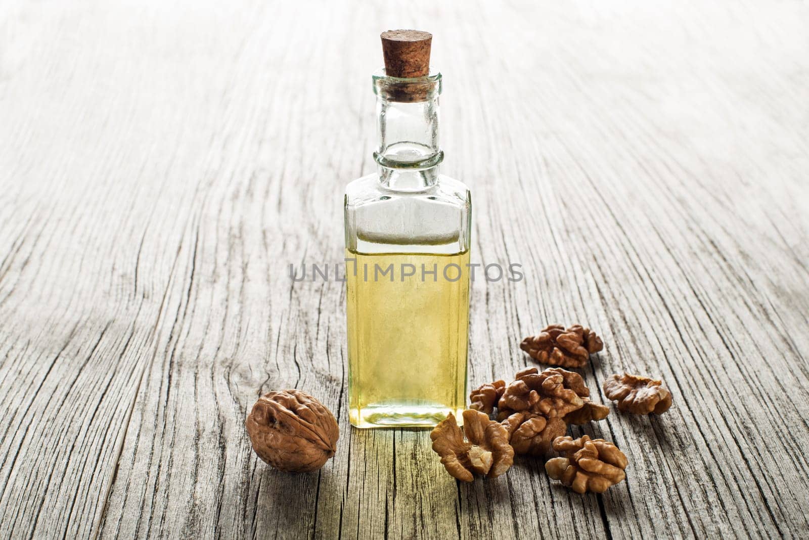 Walnut oil in a glass bottle on a wooden background