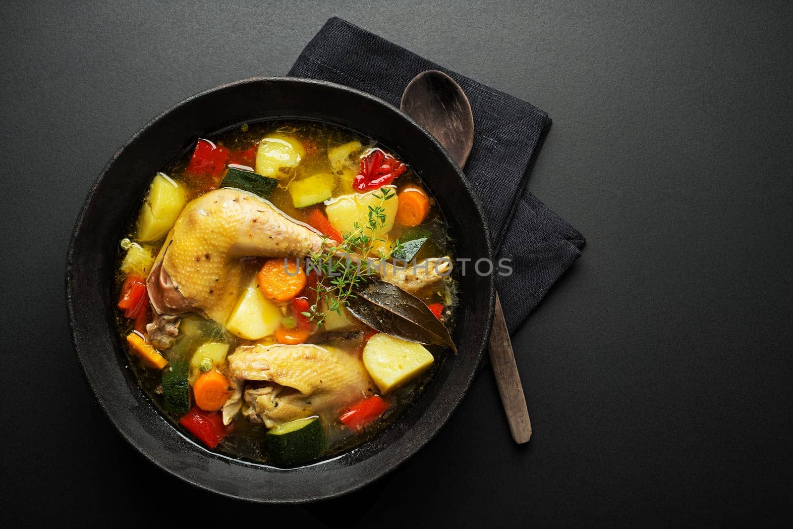 Chicken soup with vegetables in bowl on black background
