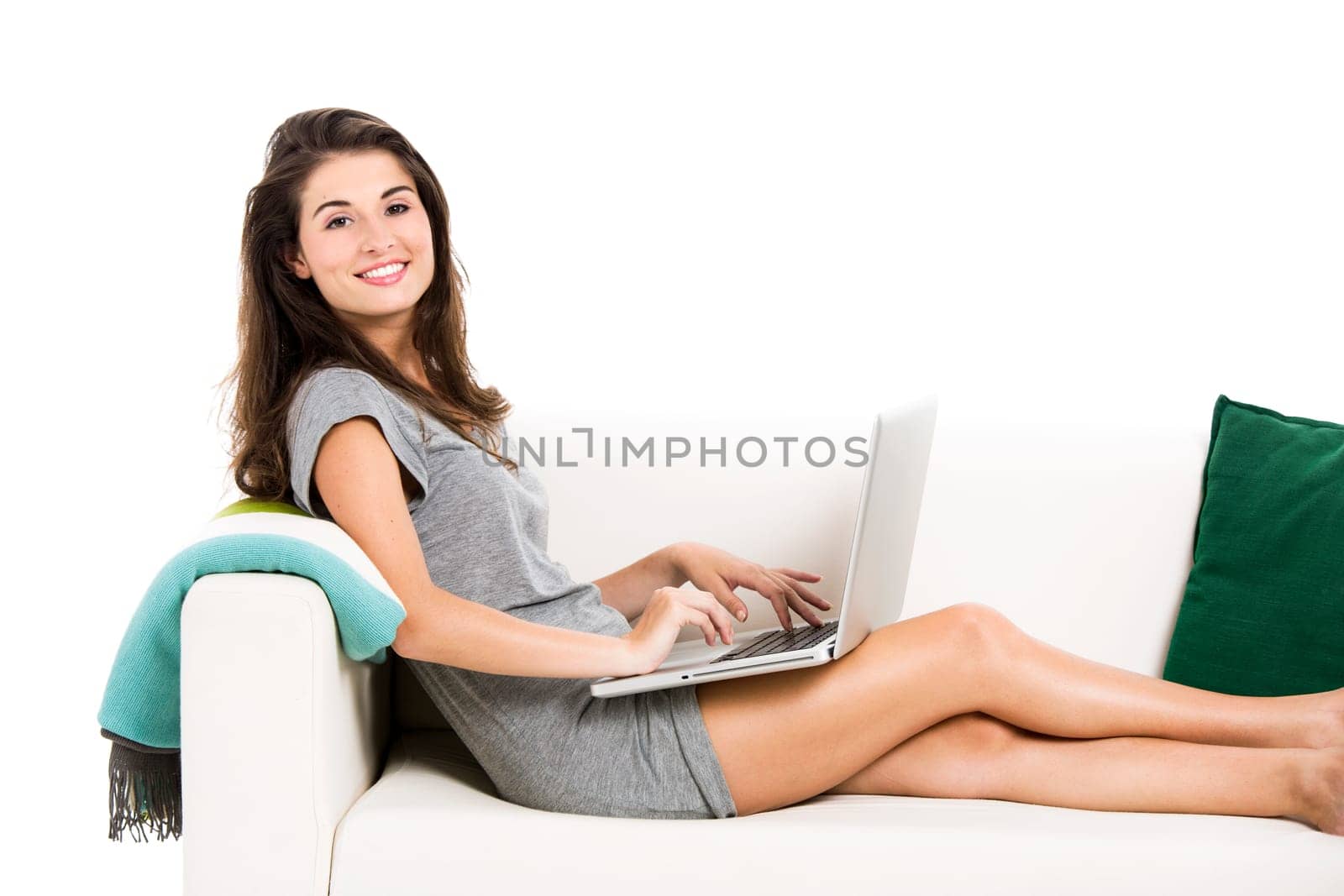 Beautiful woman on a sofa working with a laptop, isolated in white
