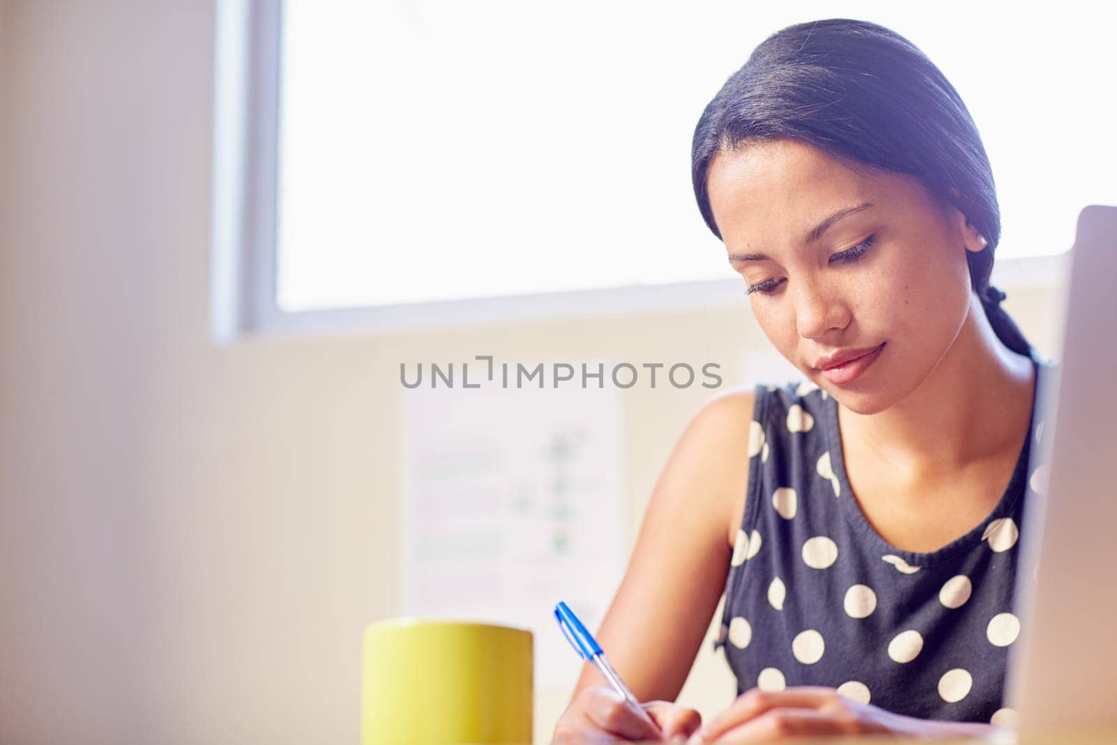 A young woman writing while sitting in her office