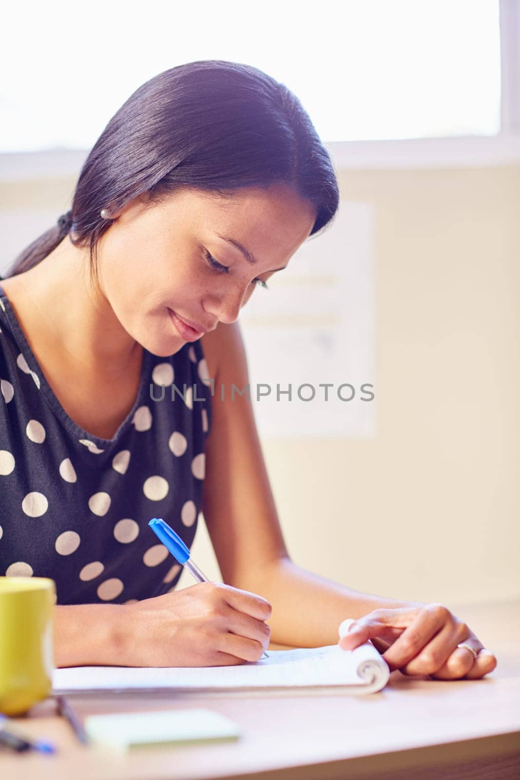 A young woman writing while sitting in her office