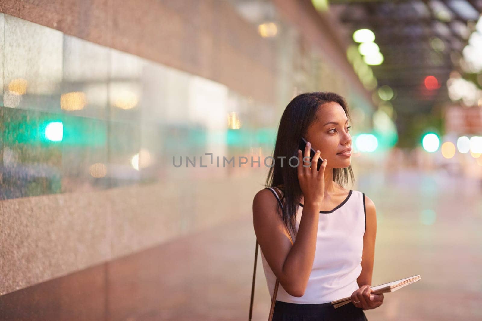 A young businesswoman talking on her phone while standing in front of an office block