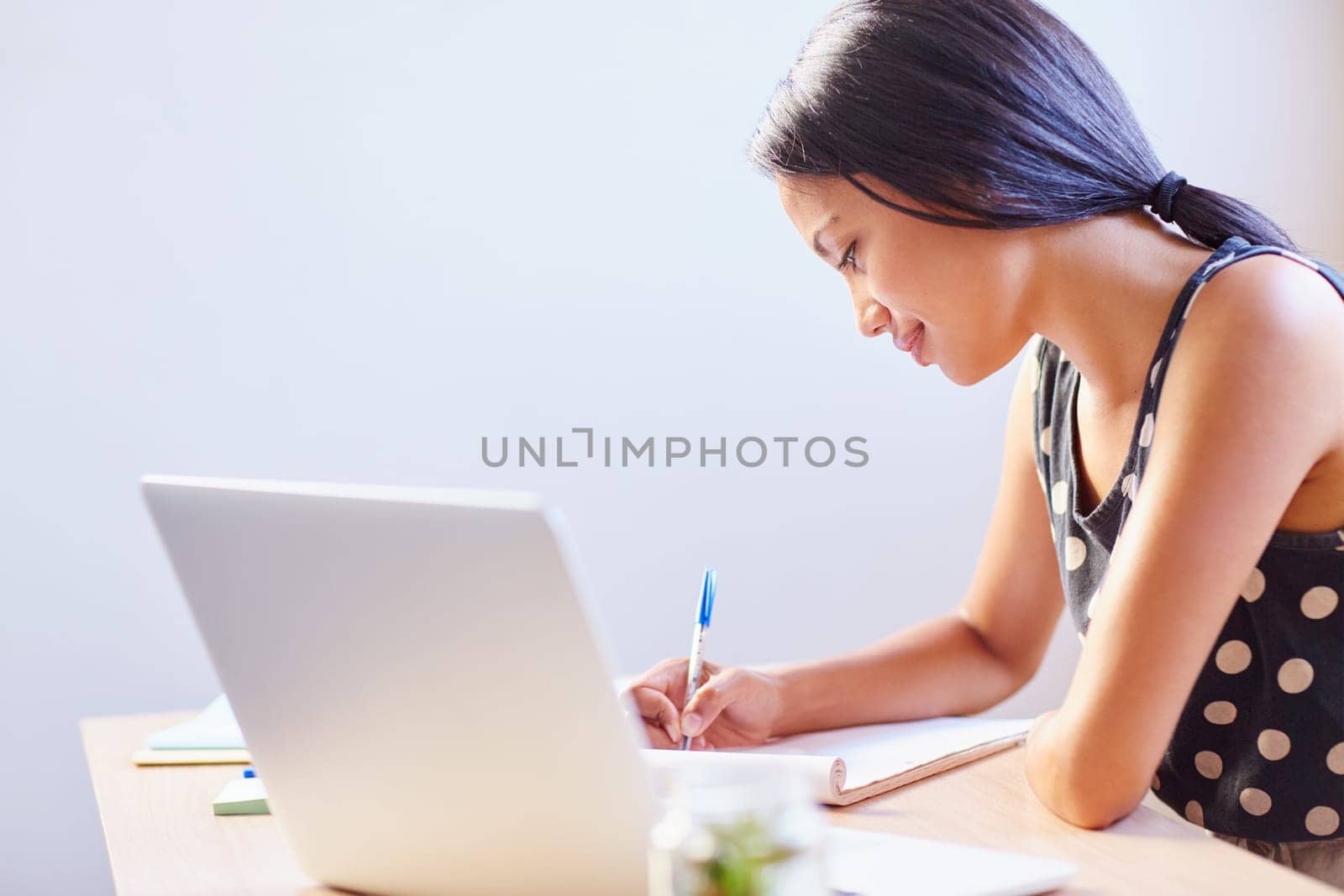 A young woman writing while sitting in her office