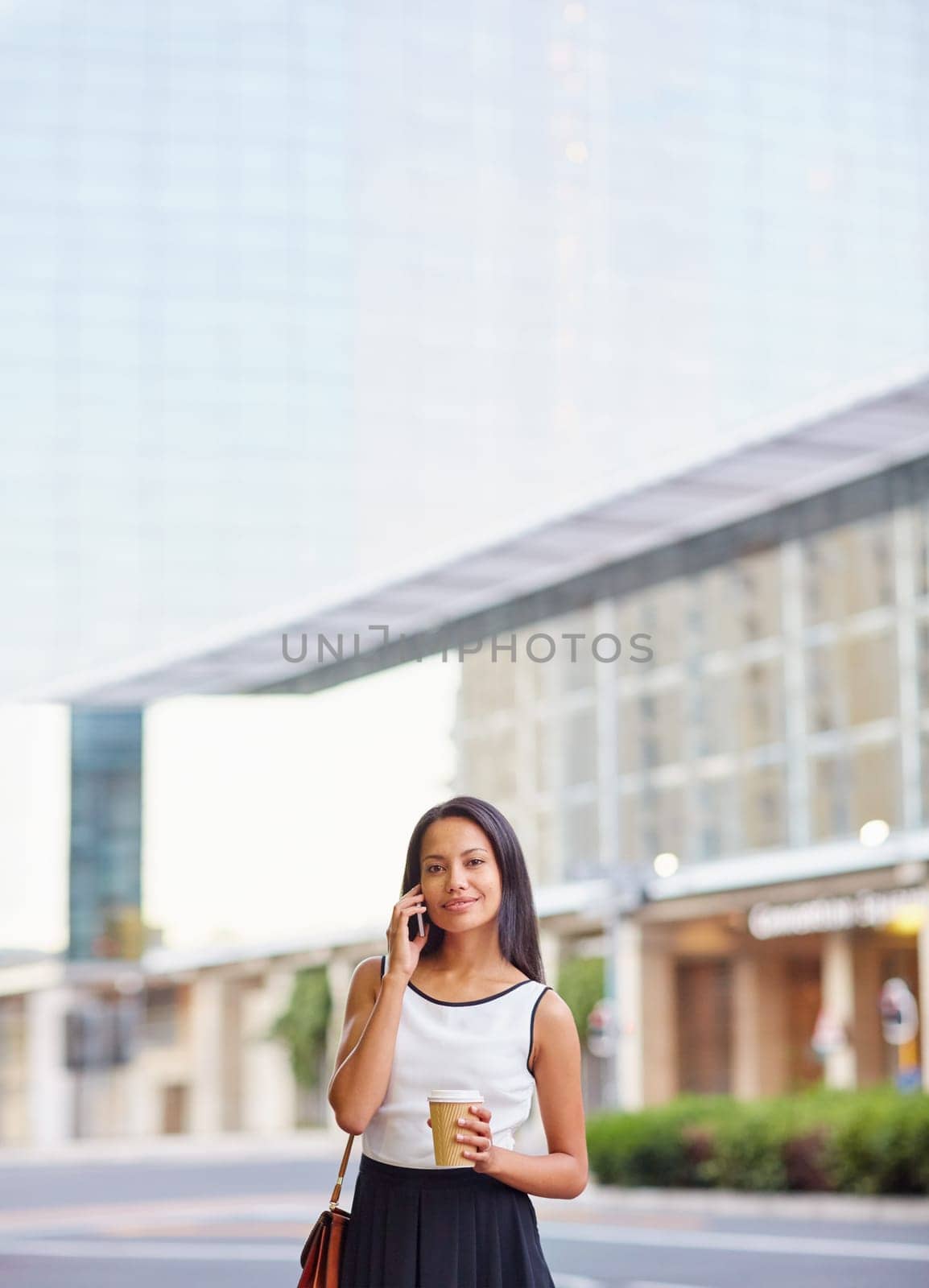 A young businesswoman talking on her phone while standing in front of an office block