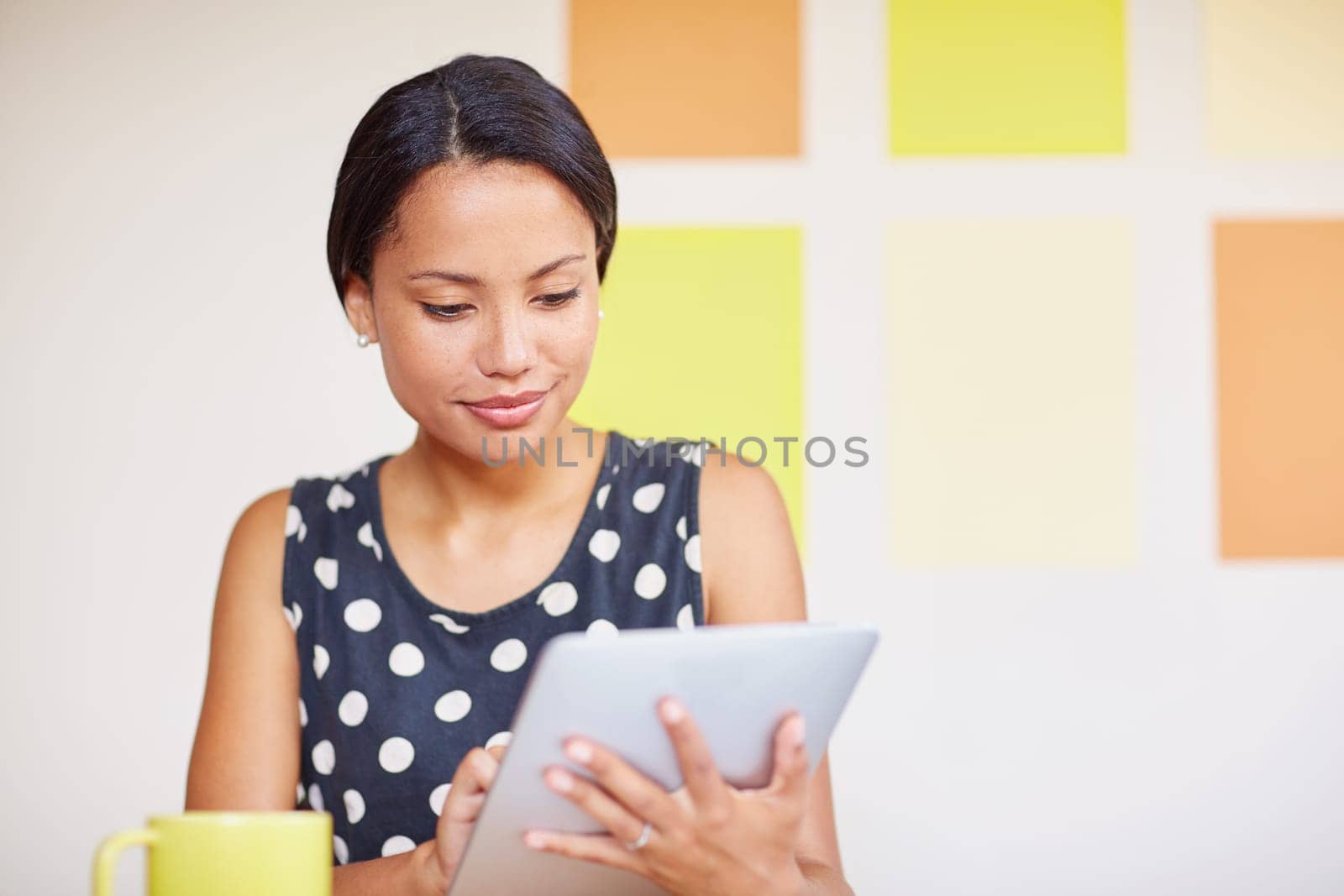 A young woman working on her digital tablet in her office