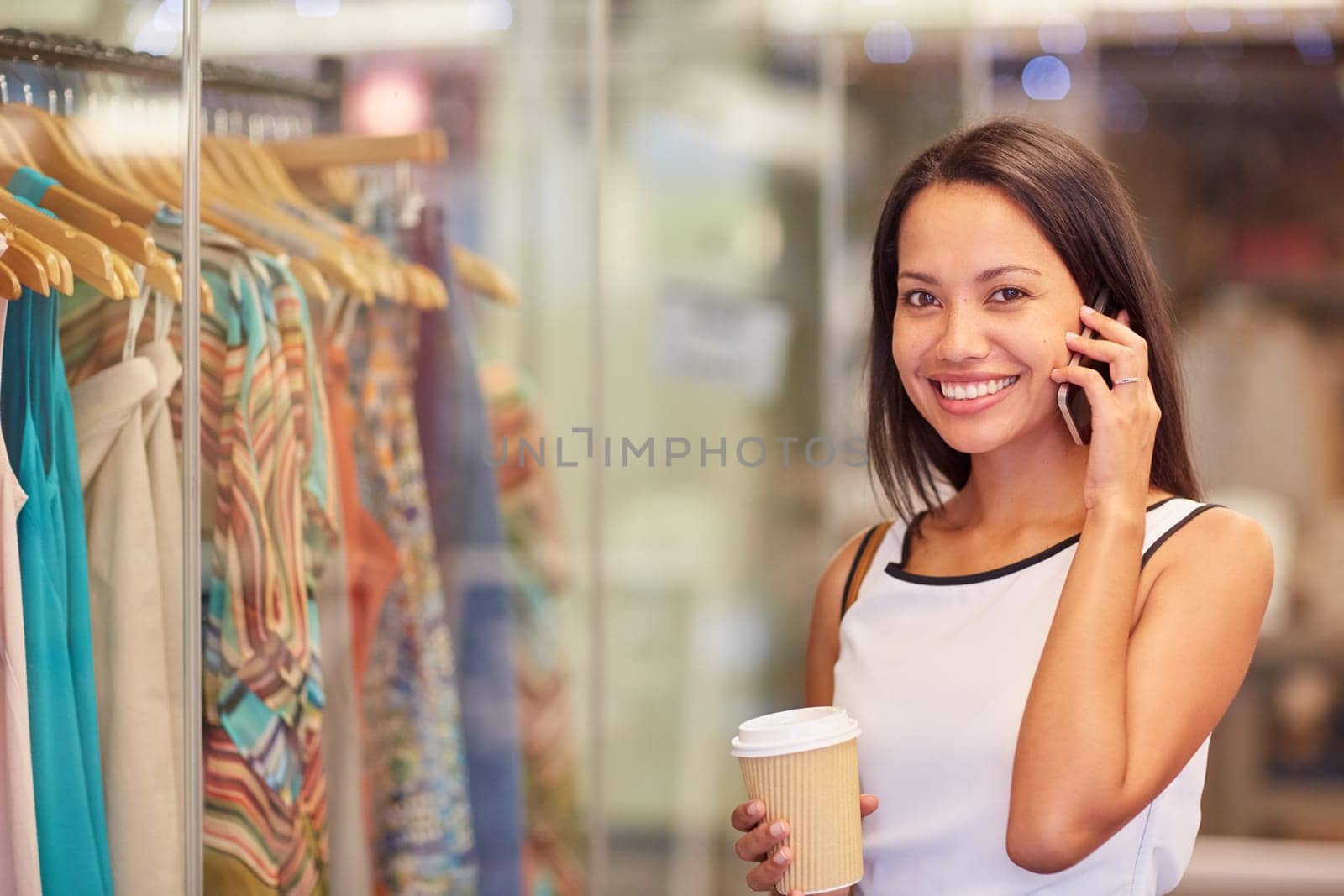 A young woman talking on the phone while browsing for clothes in a shop