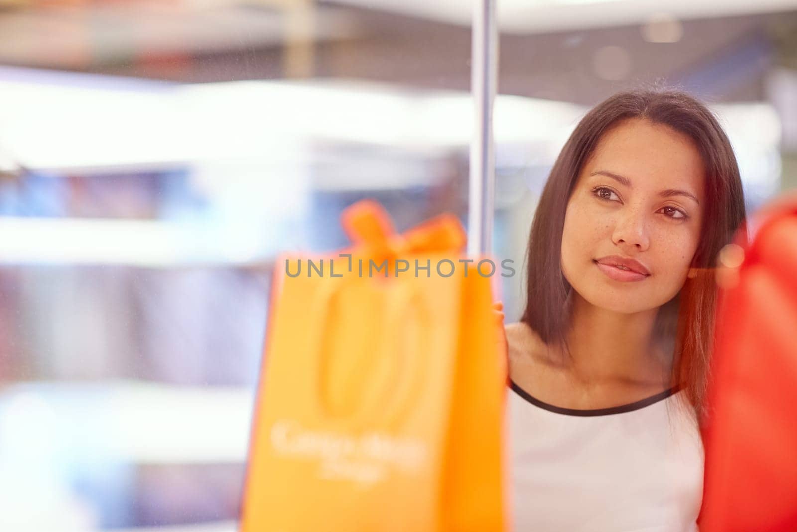 A young woman looking at a handbag through a shop window