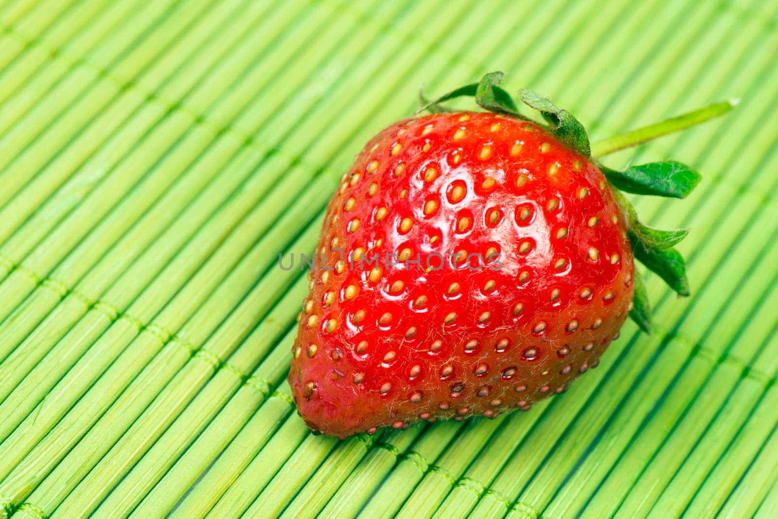 Red ripe fresh strawberry on green background.