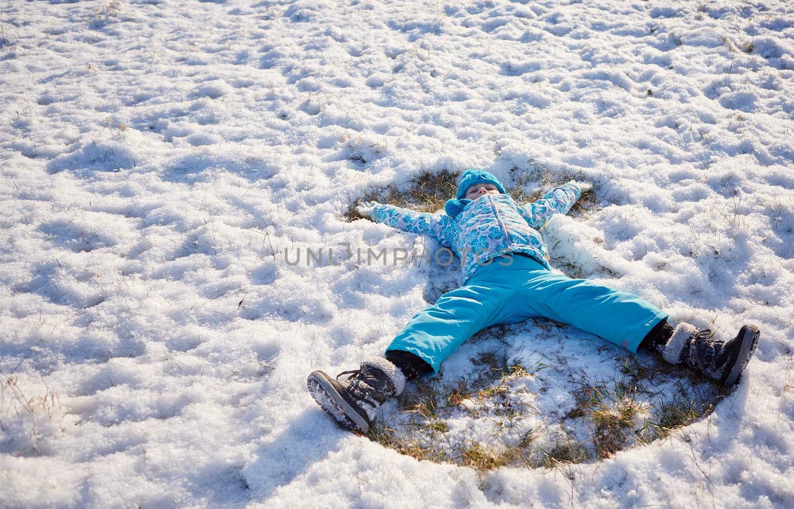 Shot of a little girl making snow angels in a snowy field