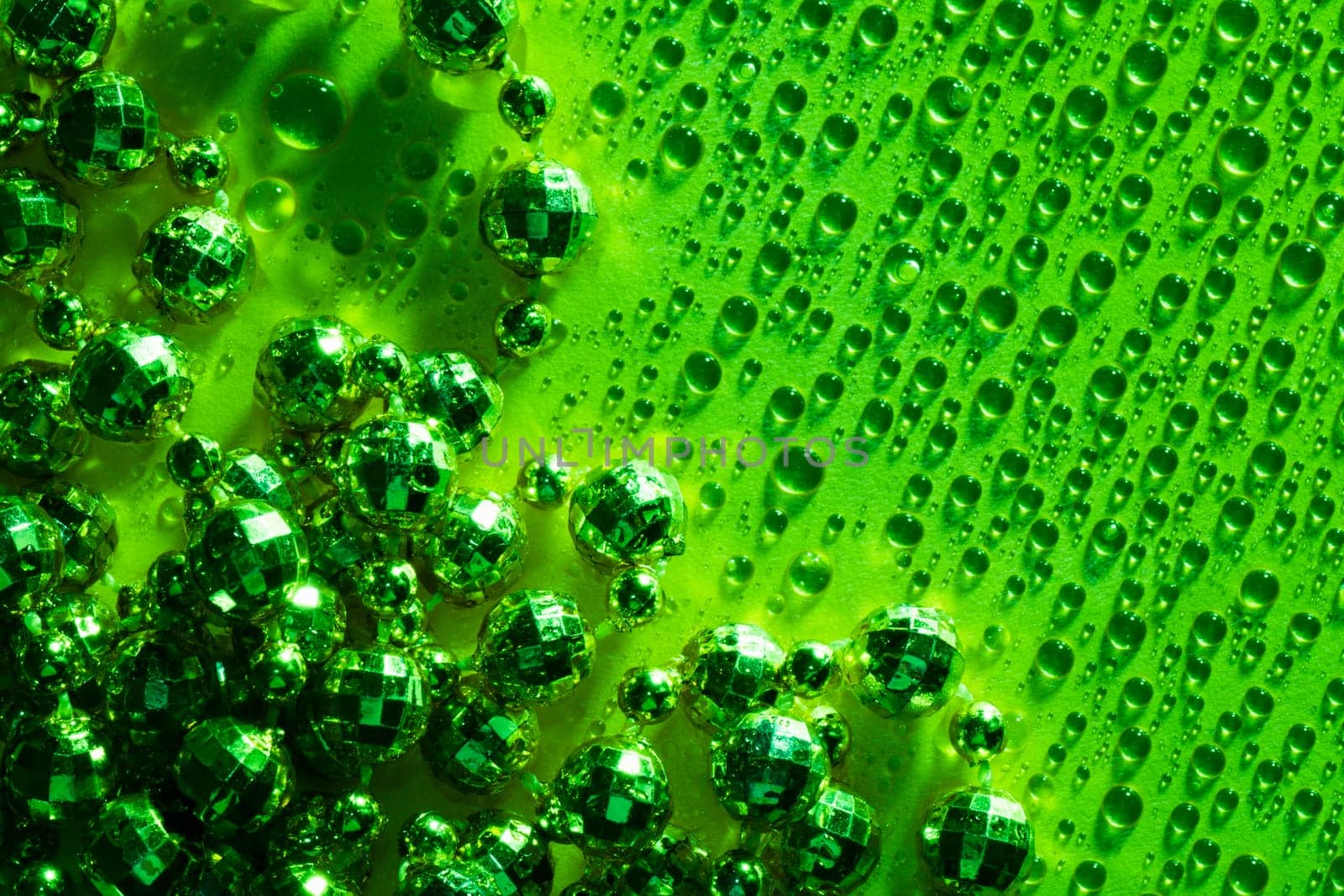 Green pearls of necklace on green background with water drops.