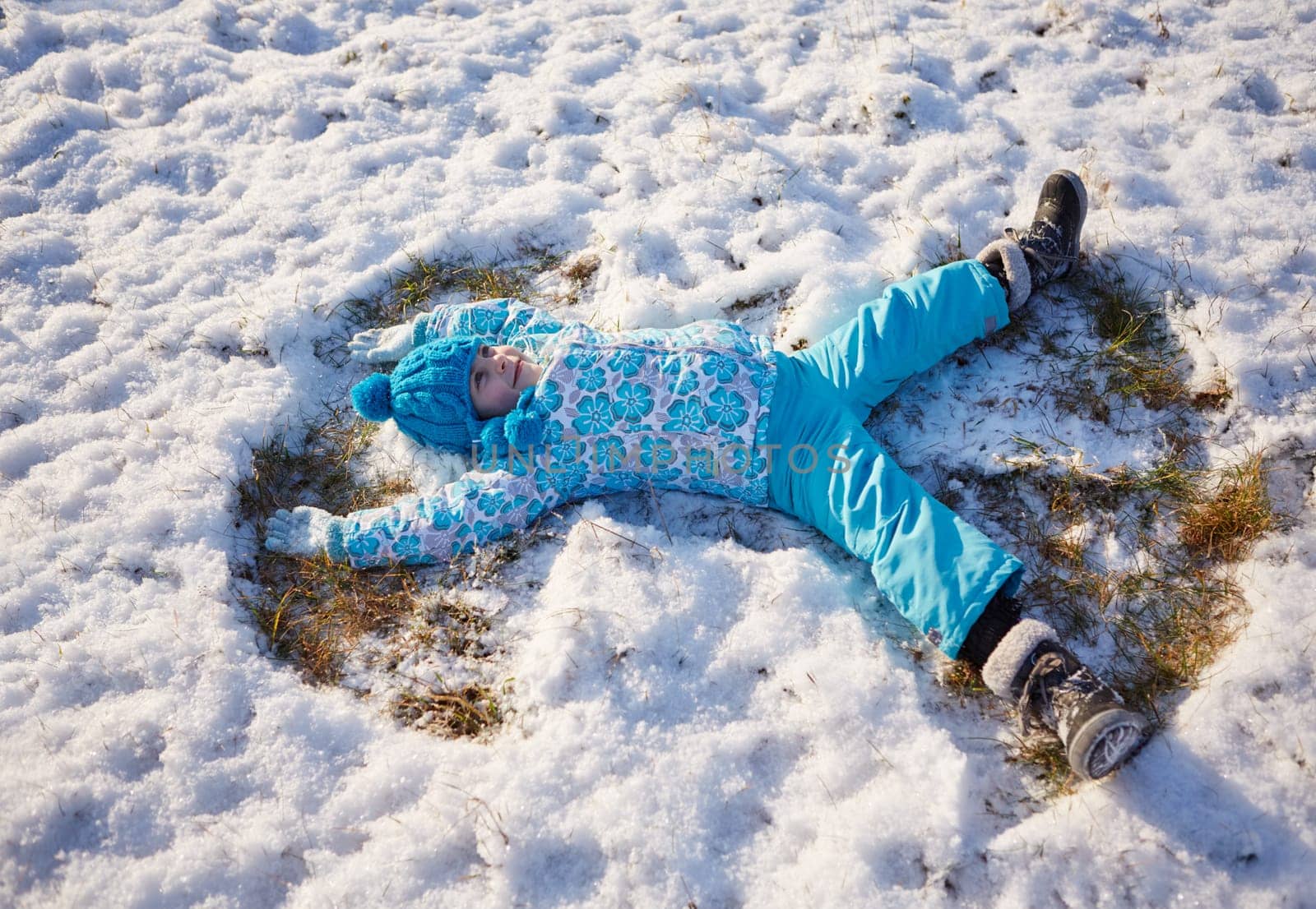 Shot of a little girl making snow angels in a snowy field