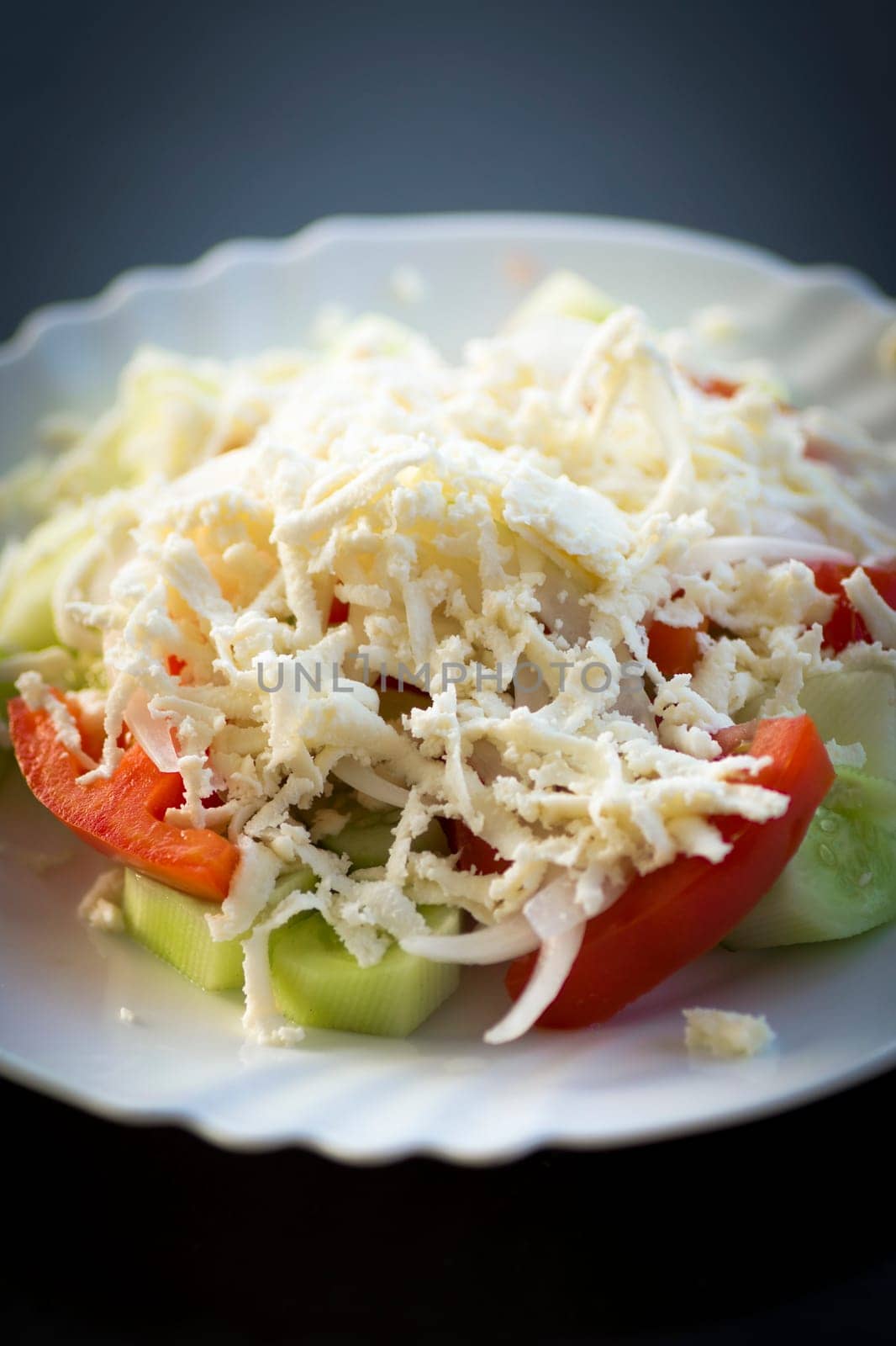 Traditional serbian salad on white plate on dark background.