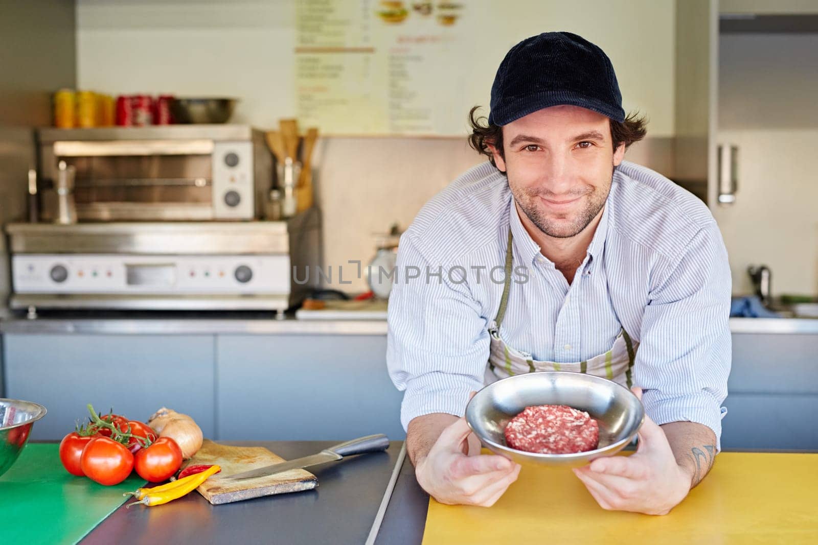Takeaway food entrepeneur standing proudly next to a bowl of fresh high-quality minced red meat with which he makes his hamburger patties