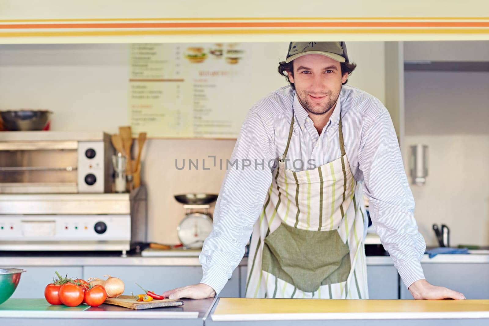 Young male entrepeneur standing confidently in his food stall where he makes and sells takeaway food.