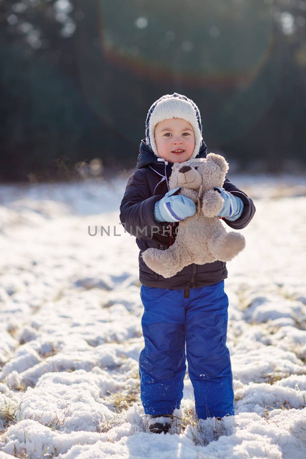 Full length shot of an adorable little boy holding his teddy bear outdoors on a snowy winter's day