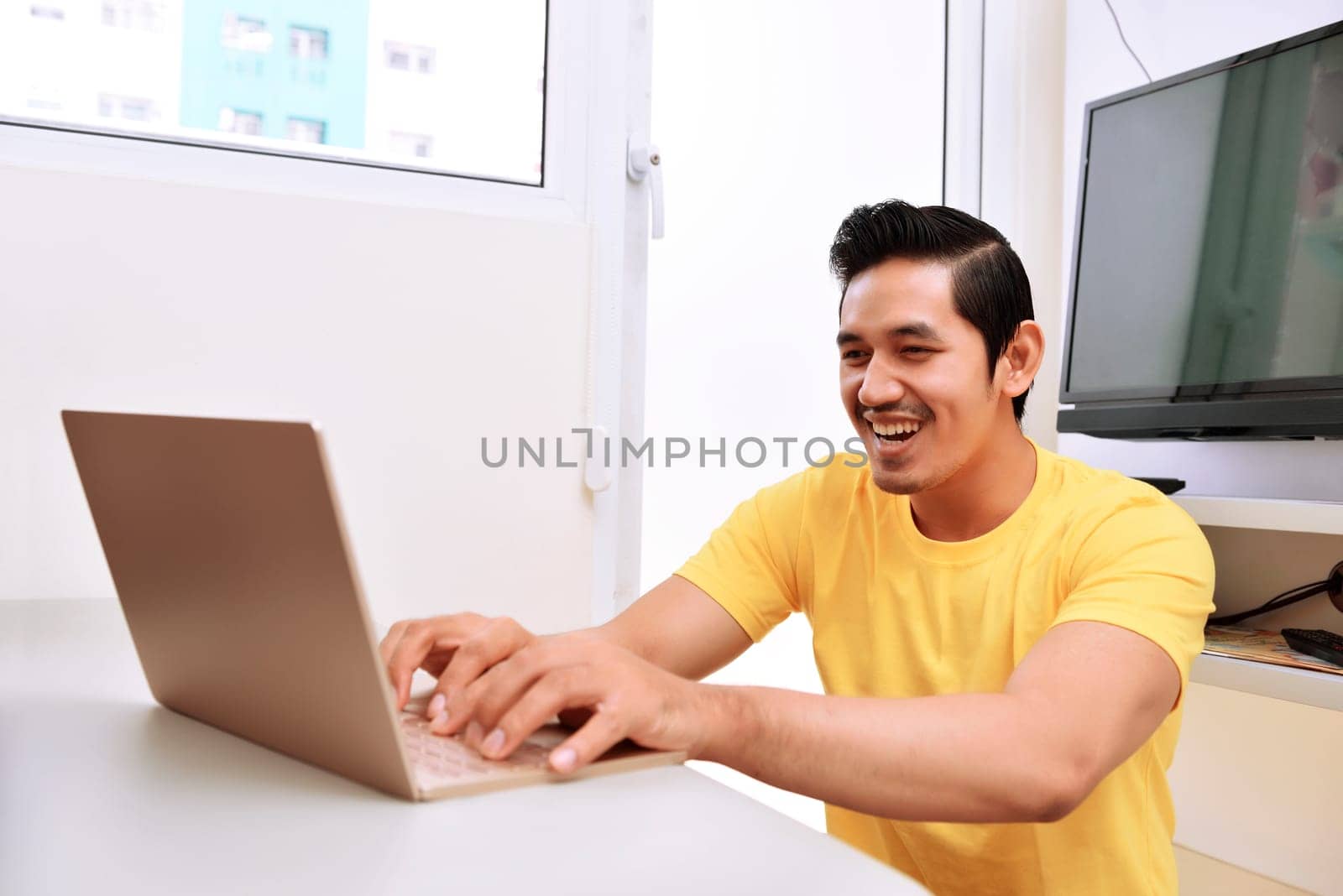 Happy asian man sitting with laptop in the living room
