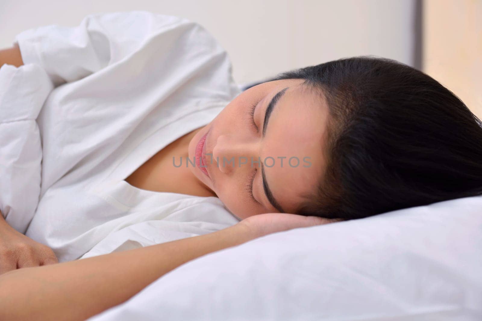 Young asian woman sleeping with head lying on hand in the bedroom