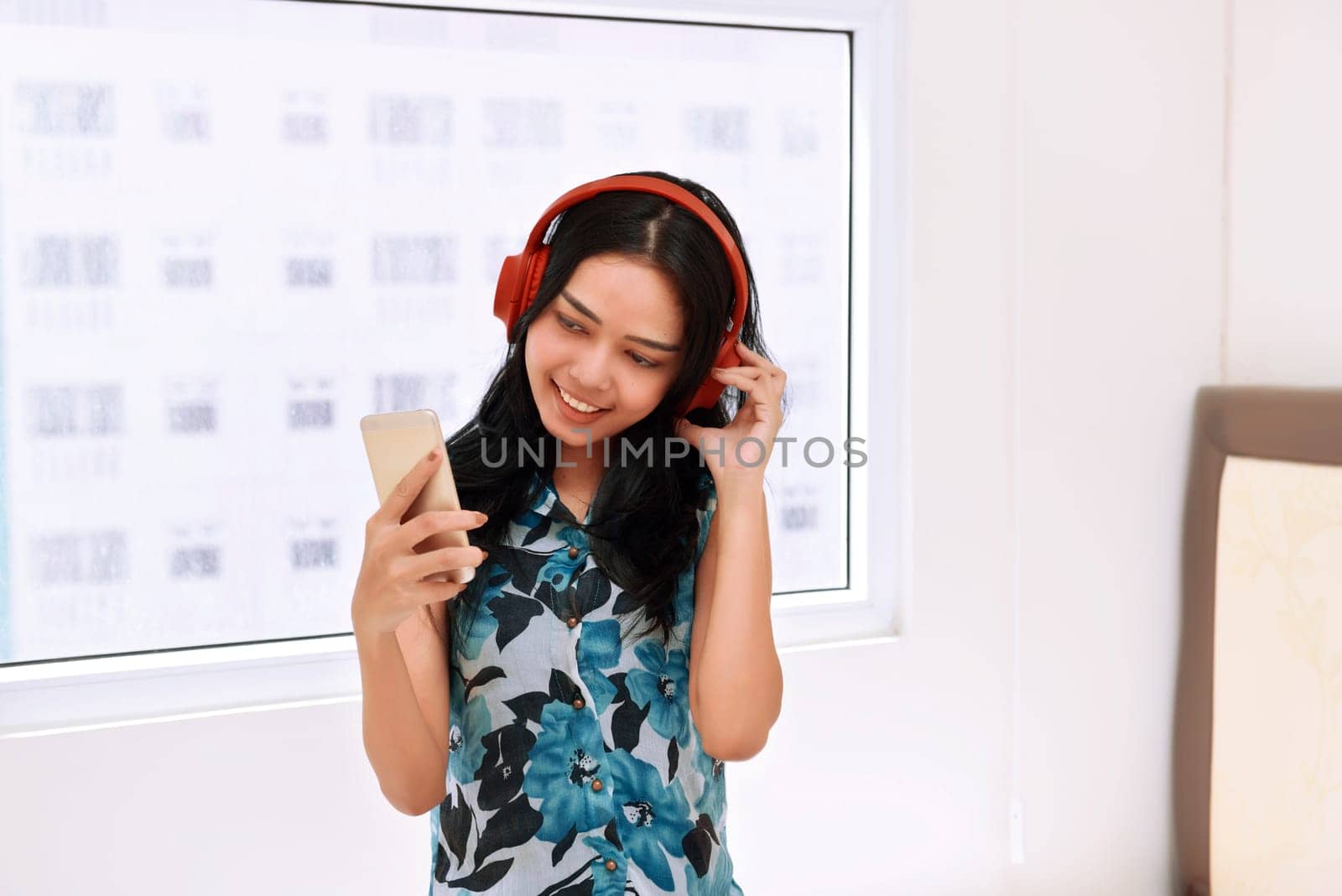 Happy asian woman listening music with headphone on the bedroom