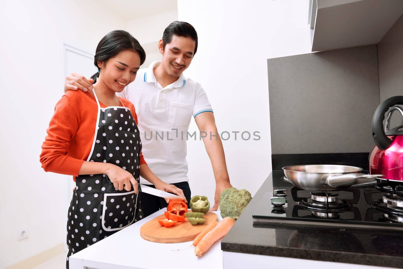 Portrait of asian couple smiling and cooking together in the kitchen