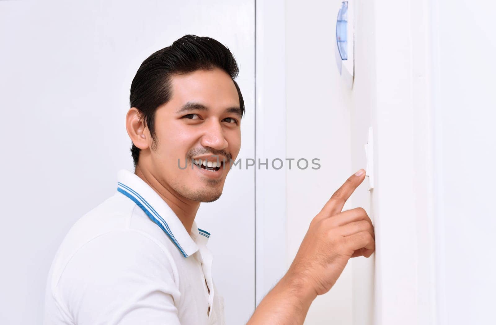 Handsome asian man turning off the light with wall switch in the home