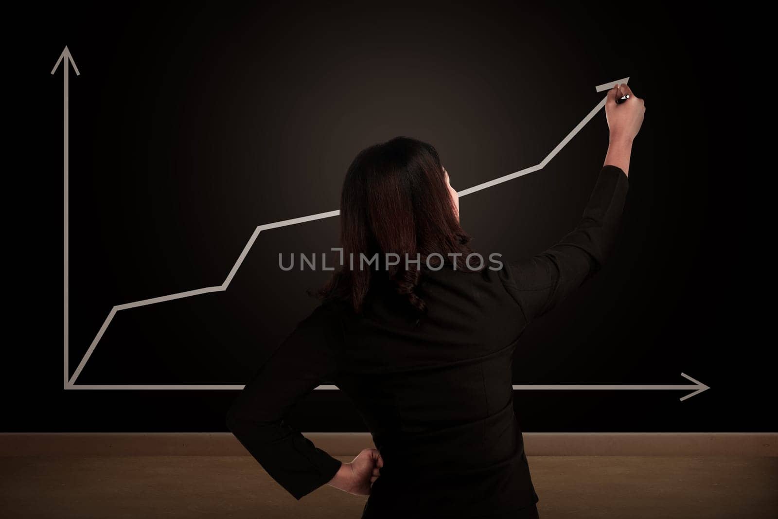 Business woman drawing increasing chart on the chalk board. Business success concept