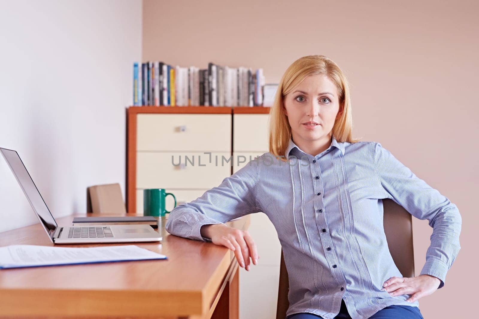 A young businesswoman smiling at the camera while sitting in her office