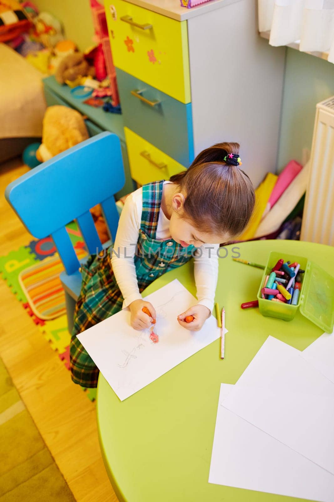 A little girl drawing in her room