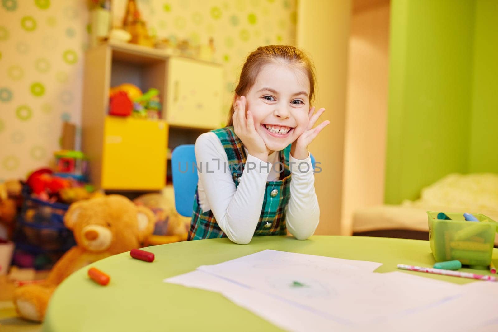 A happy little girl sitting at her table with art supplies