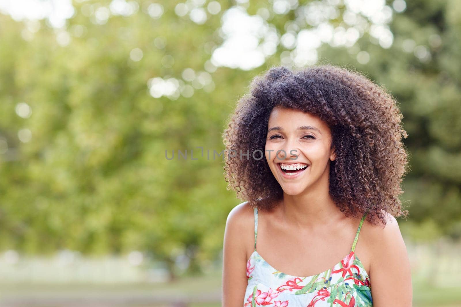 Happy mixed reac woman laughing joyfully in a green park