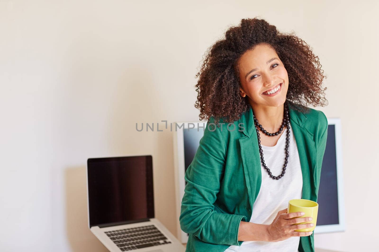 Mixed race businesswoman smiling while standing in front of her desk with a cup of coffee