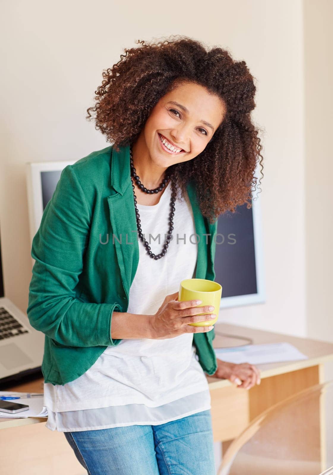 Beautiful young mixed race businesswoman standing at her desk, while holding a cup of coffee