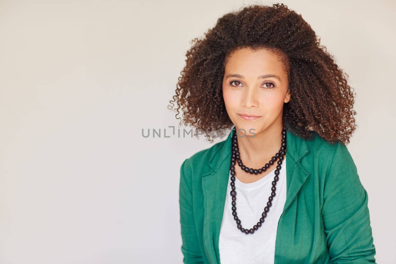 Beautiful young mixed race businesswoman looking at the camera confidently wearing a green jacket