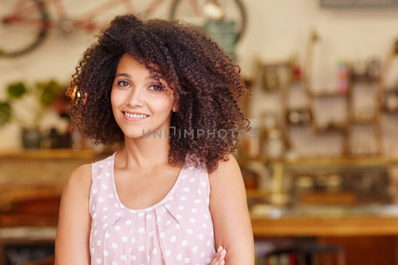 Closeup of a gorgeous mixed race woman with afro hair smiling at the camera in a coffee shop