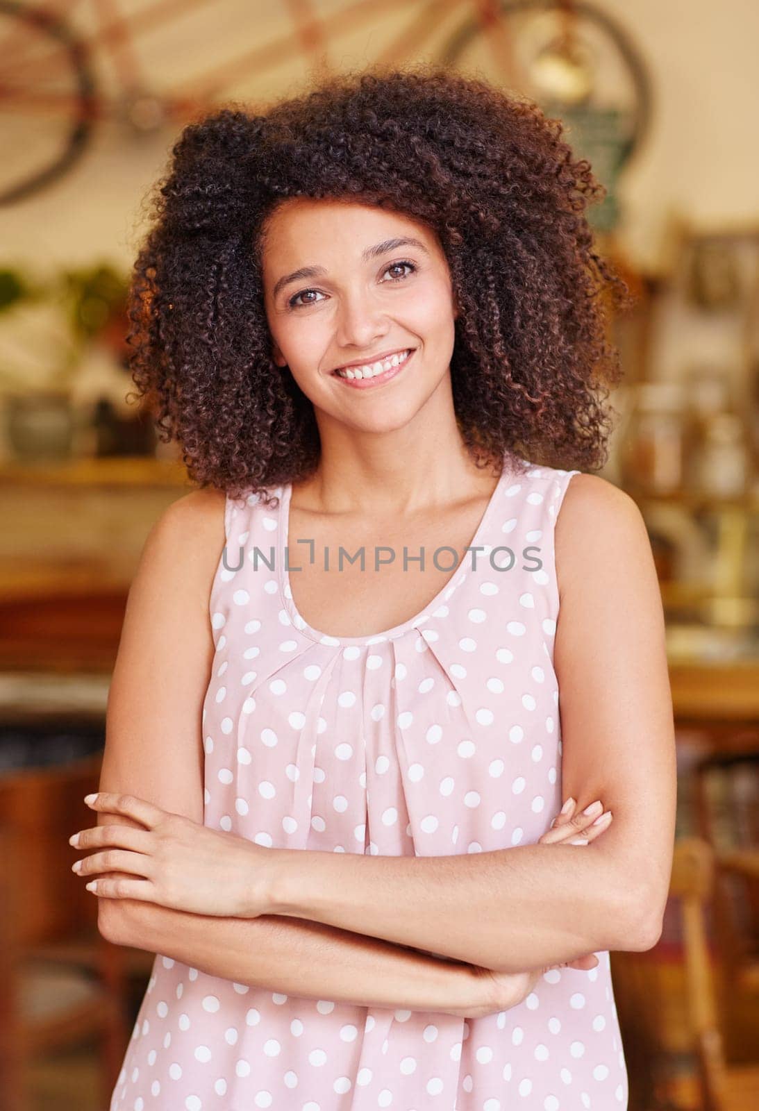 Beautiful young mixed race woman in her coffee shop smiling and standing with her arms crossed confidently
