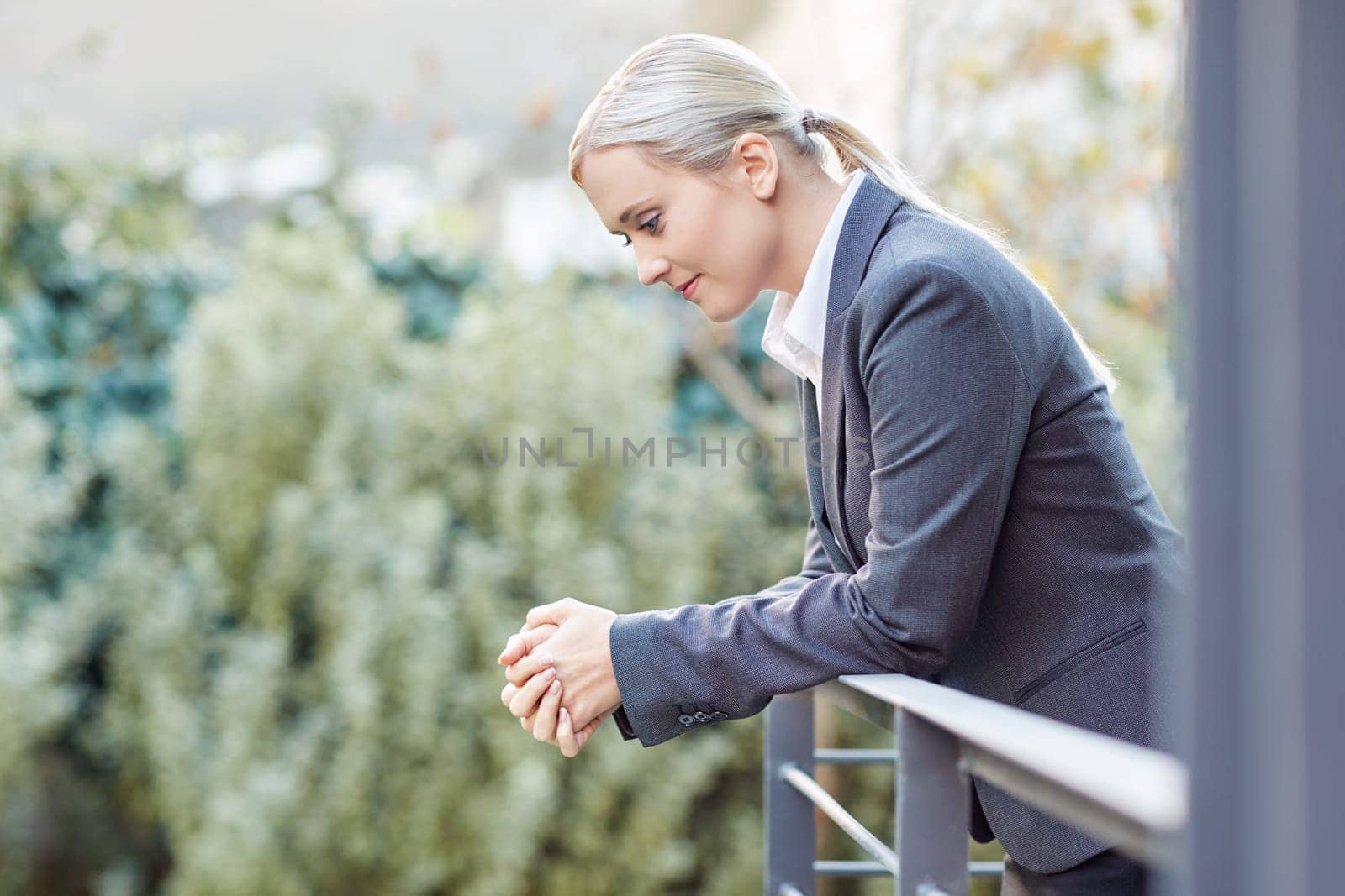 A young businesswoman leaning against the railing of her office balcony