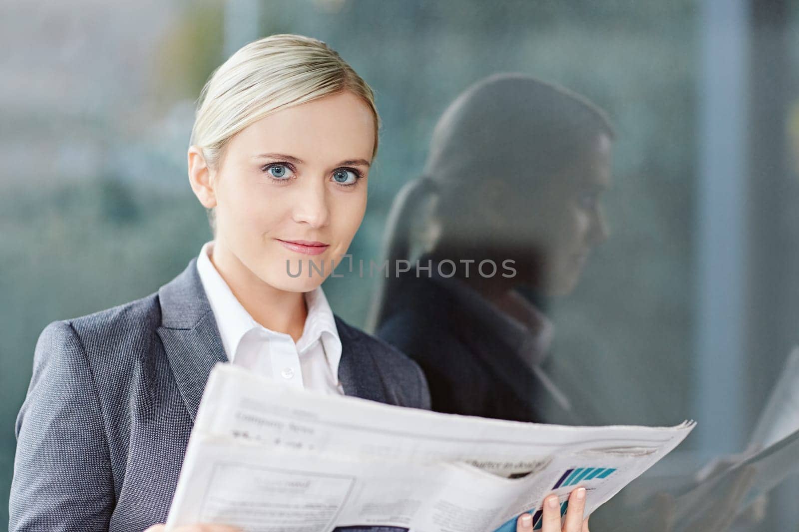 A young businesswoman reading the newpaper outside her office