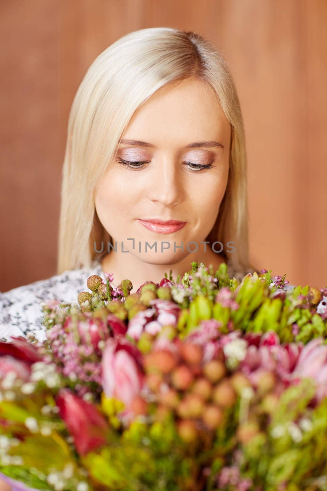Portrait of a beautiful young woman holding flowers and looking at them