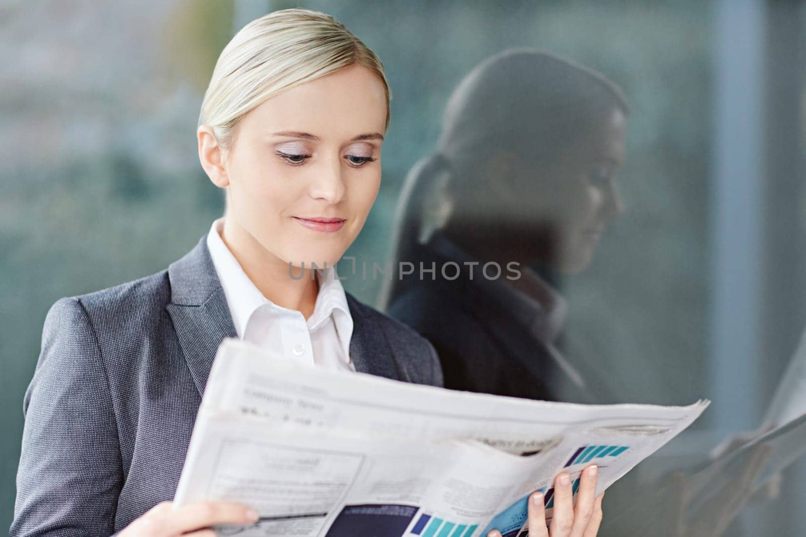 A young businesswoman reading the newpaper outside her office