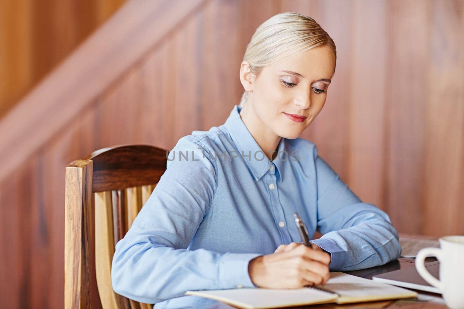 A young businesswoman taking notes, inside wooden office
