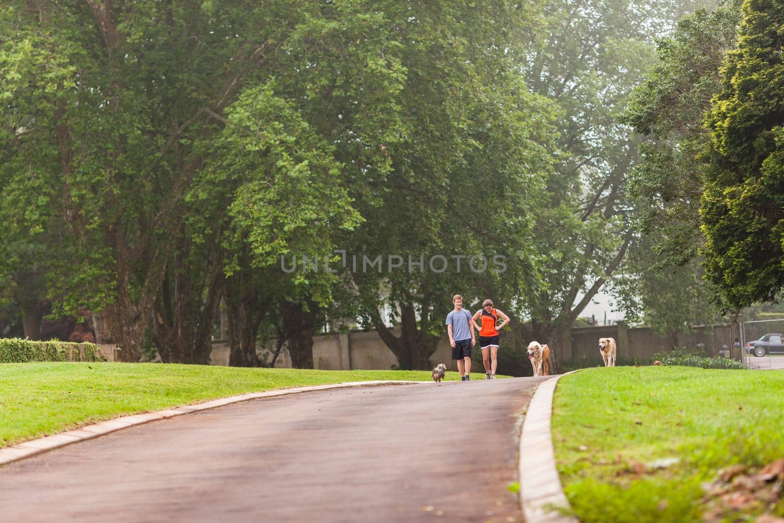 Teen boy girl warm down after fitness exercise  run on home driveway with dogs