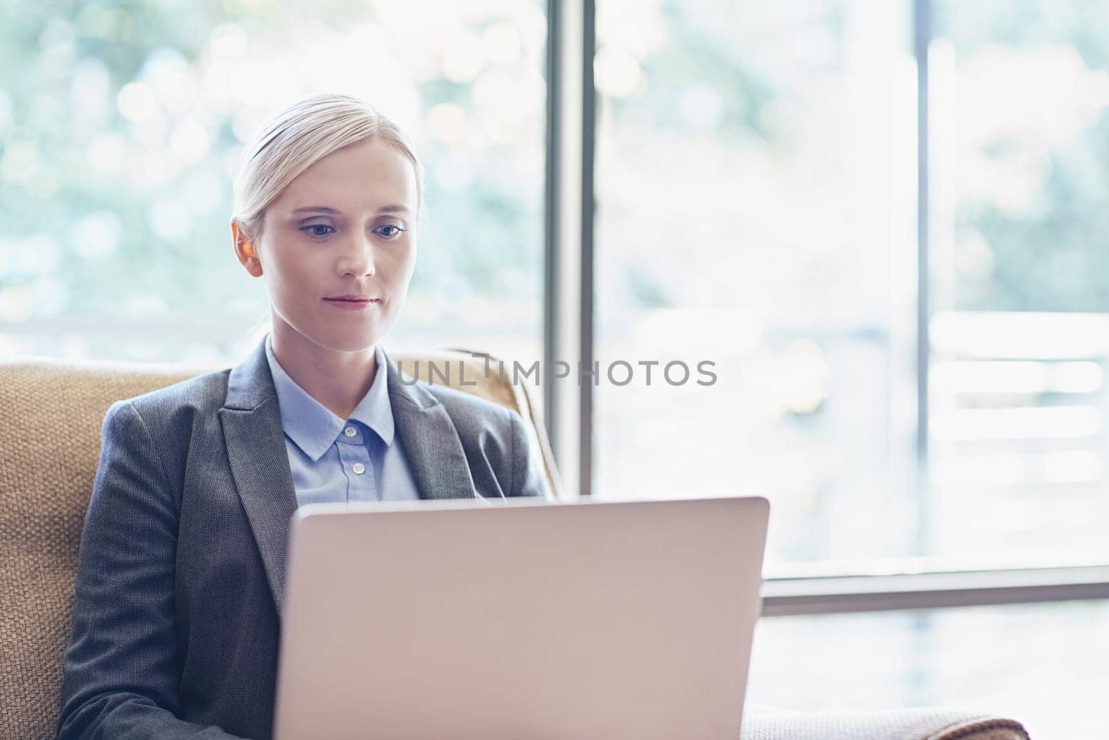A young businesswoman working on her laptop while sitting on a sofa