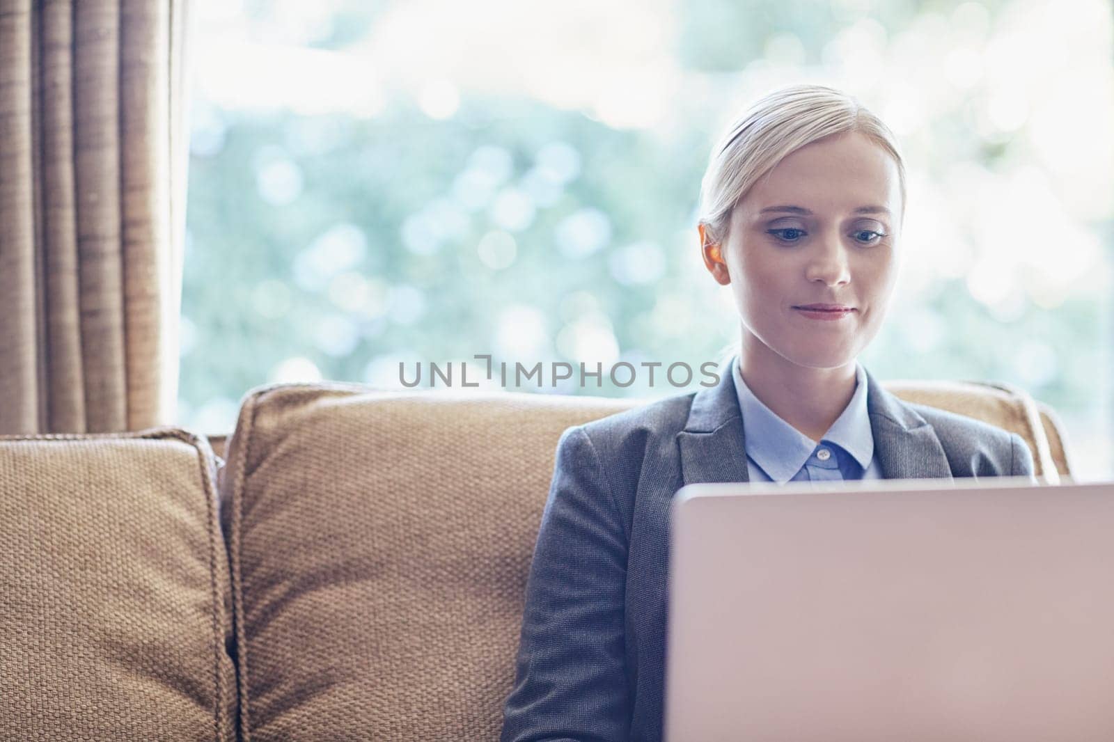 A young businesswoman working on her laptop while sitting on a sofa