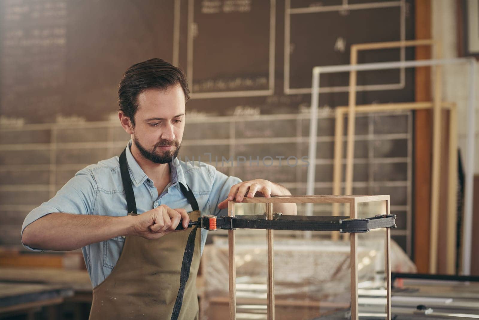 Focused capenter carefully making a wood and glass display case in his workshop with the skill of his trade
