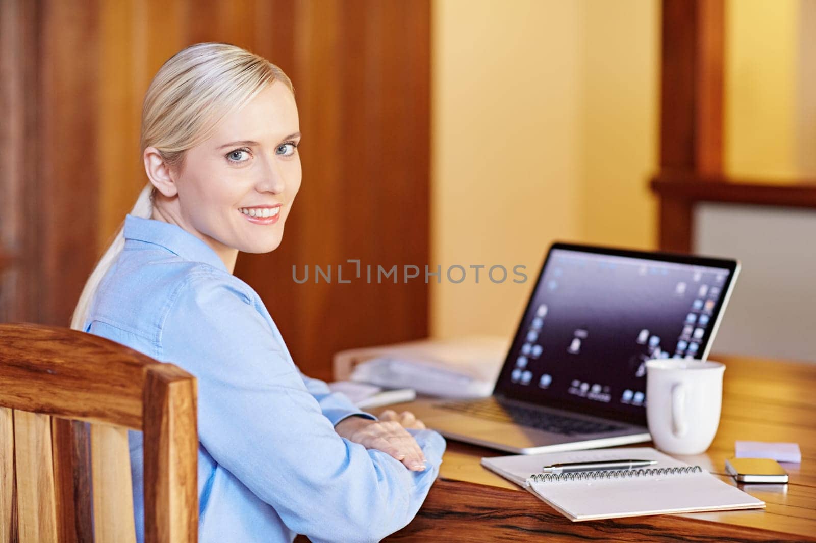Portrait of a young businesswoman at her desk, looking back in to the camera